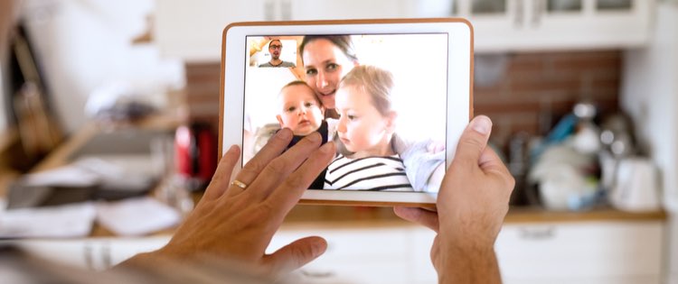 man video chatting with a woman and two children on a tablet device