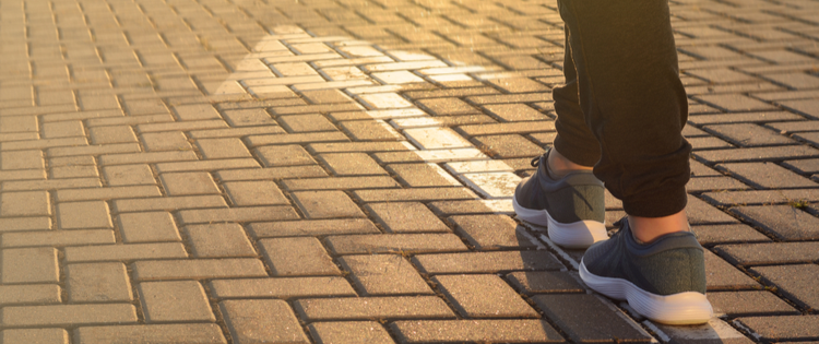 Person walking on painted arrow on a brick road.