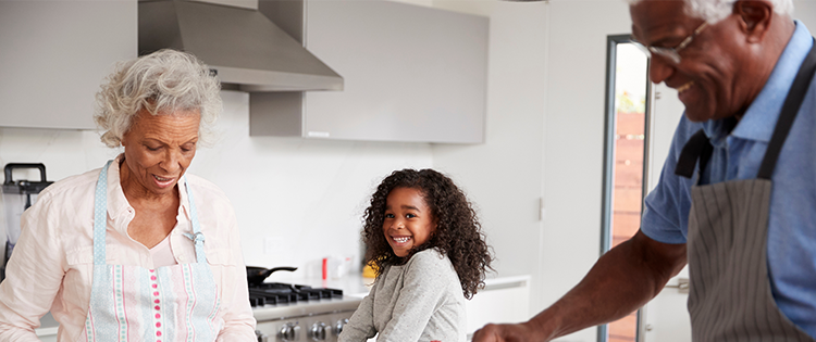 Grandparents and grandchildren cooking together in the kitchen.