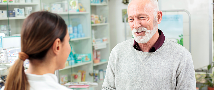 Senior man picking up prescription from pharmacy.