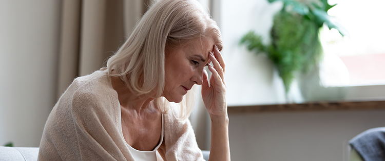 Senior woman looking upset with her head in her hand.