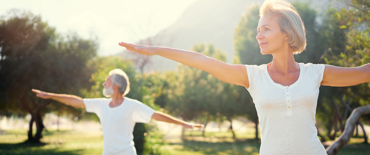 Two seniors doing yoga in the park.