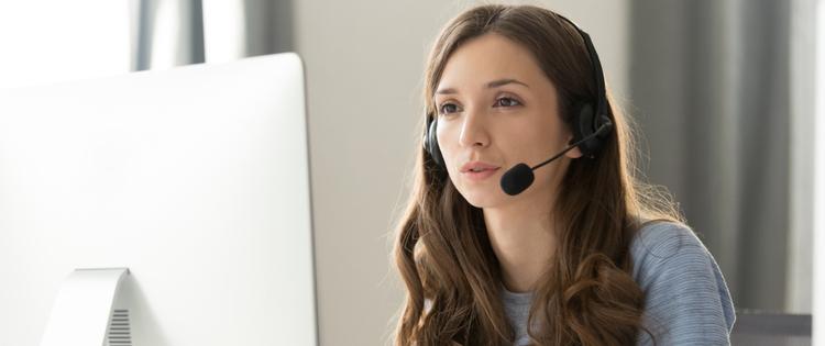 young woman with a headset on looking at computer