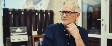 Older man with glasses sitting outside