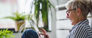 Senior woman sitting down and using tablet.