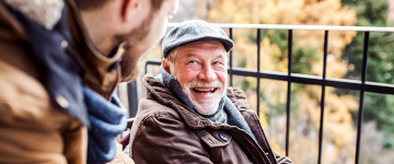 Older man laughing with his son outside