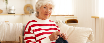 Senior woman knitting and smiling.