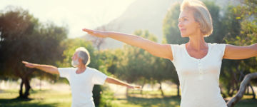 Two seniors doing yoga in the park.