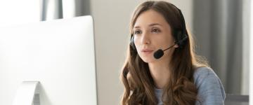 young woman with a headset on looking at computer