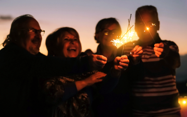 Four older adult friends with sparklers.