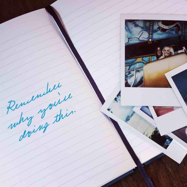 Photo of a notebook and some photographs with "Remember why you're doing this" written in the notebook