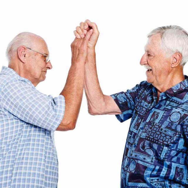 Two older men stand in a supportive high-five.